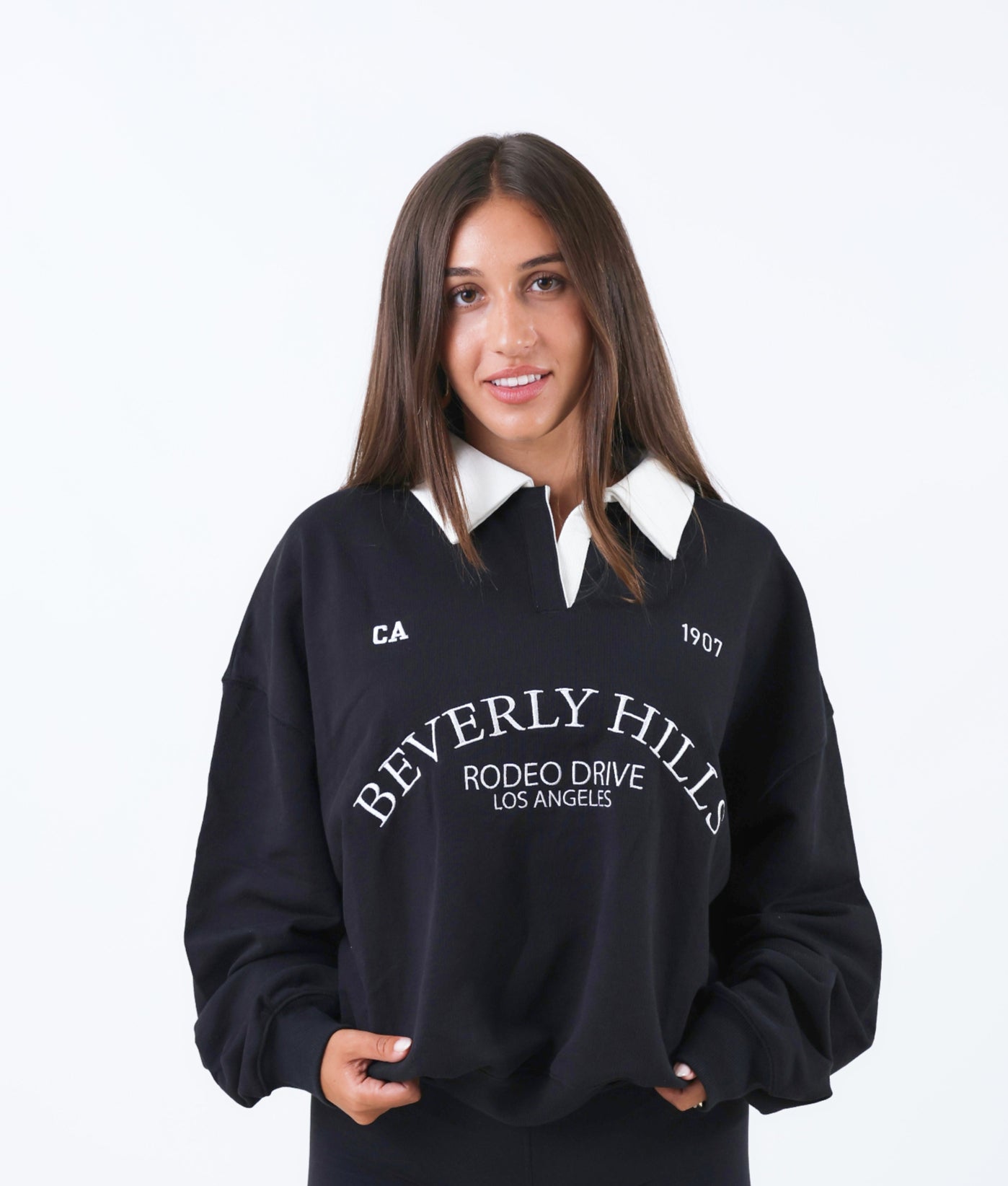 Woman wearing a black 'Beverly Hills' sweatshirt with a white collar on a white background