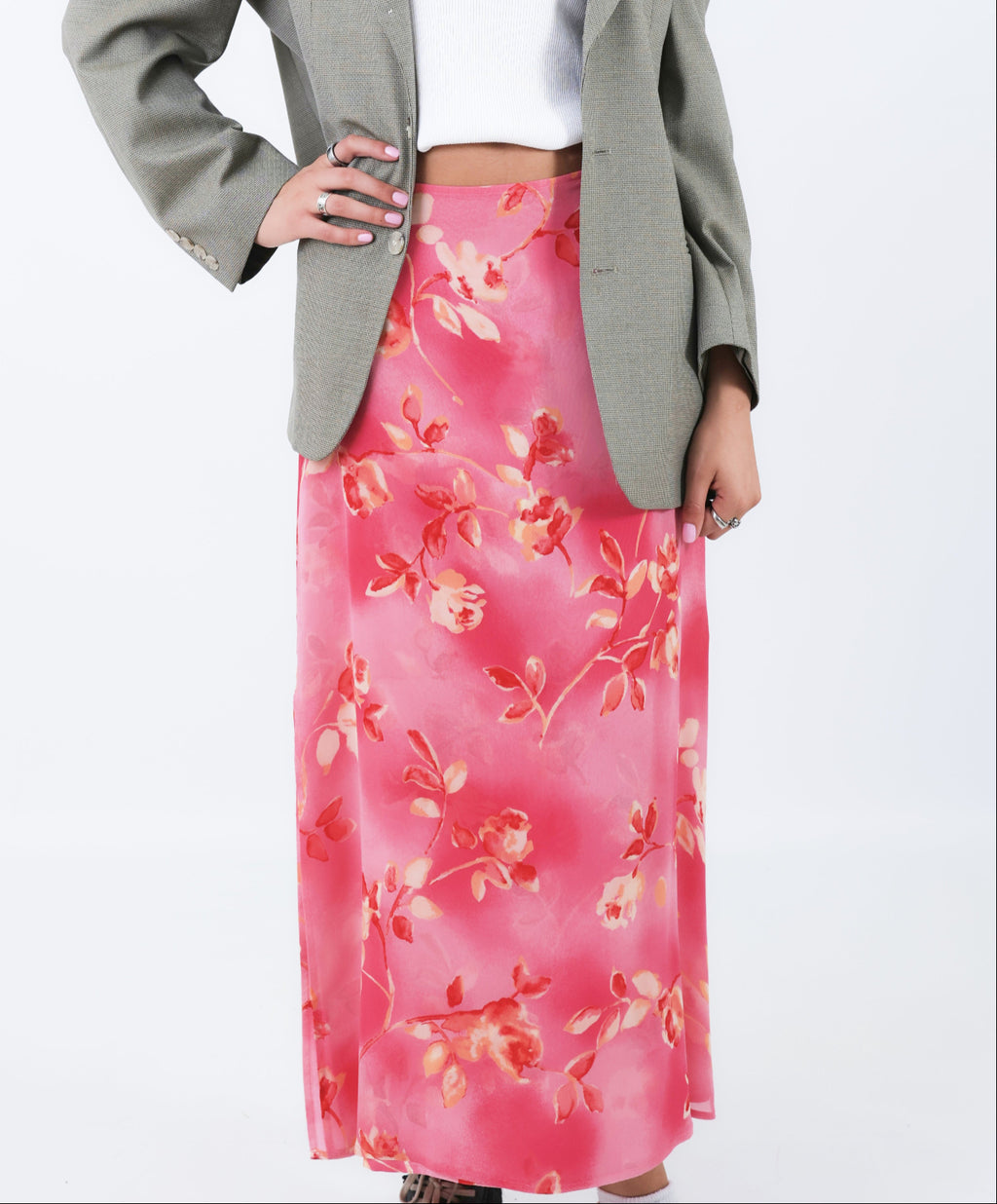 Woman wearing a gray blazer and pink floral skirt on a white background