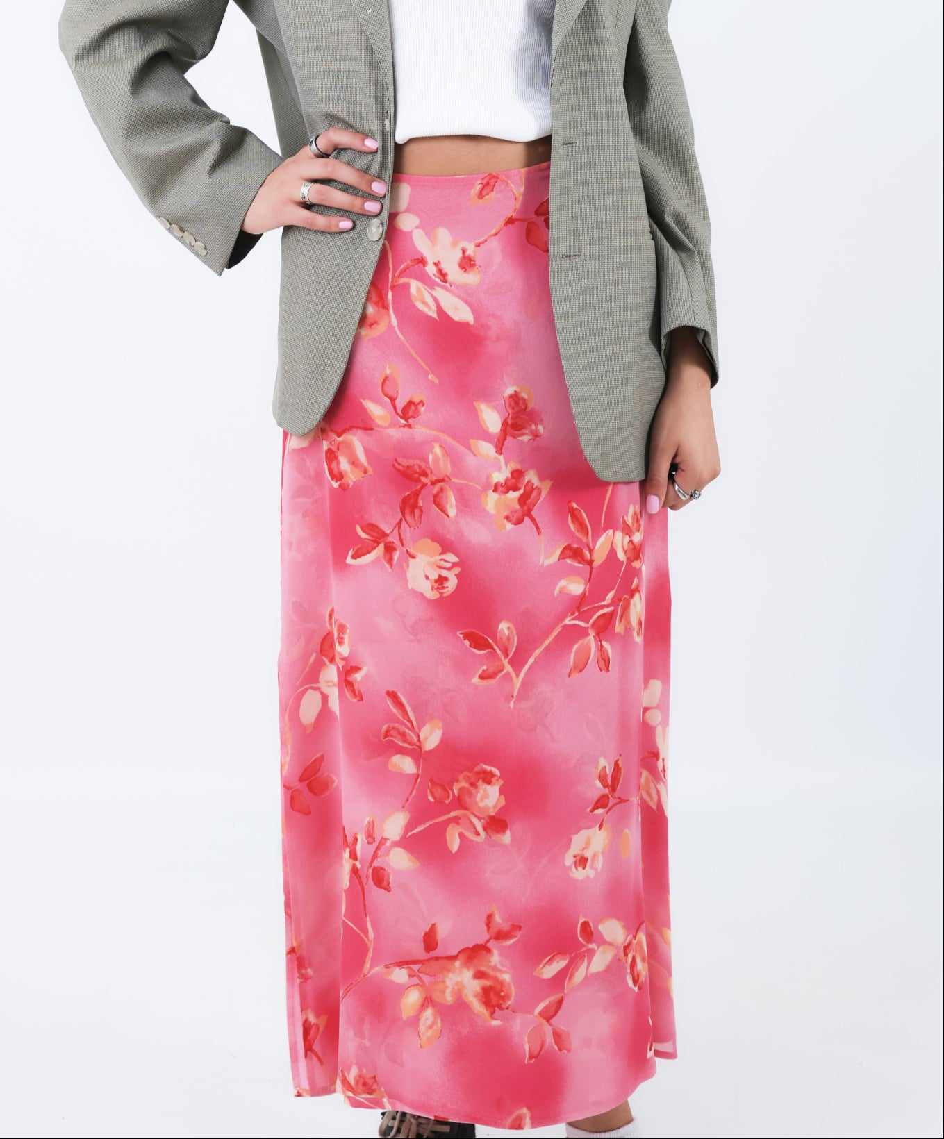 Woman wearing a gray blazer and pink floral skirt on a white background