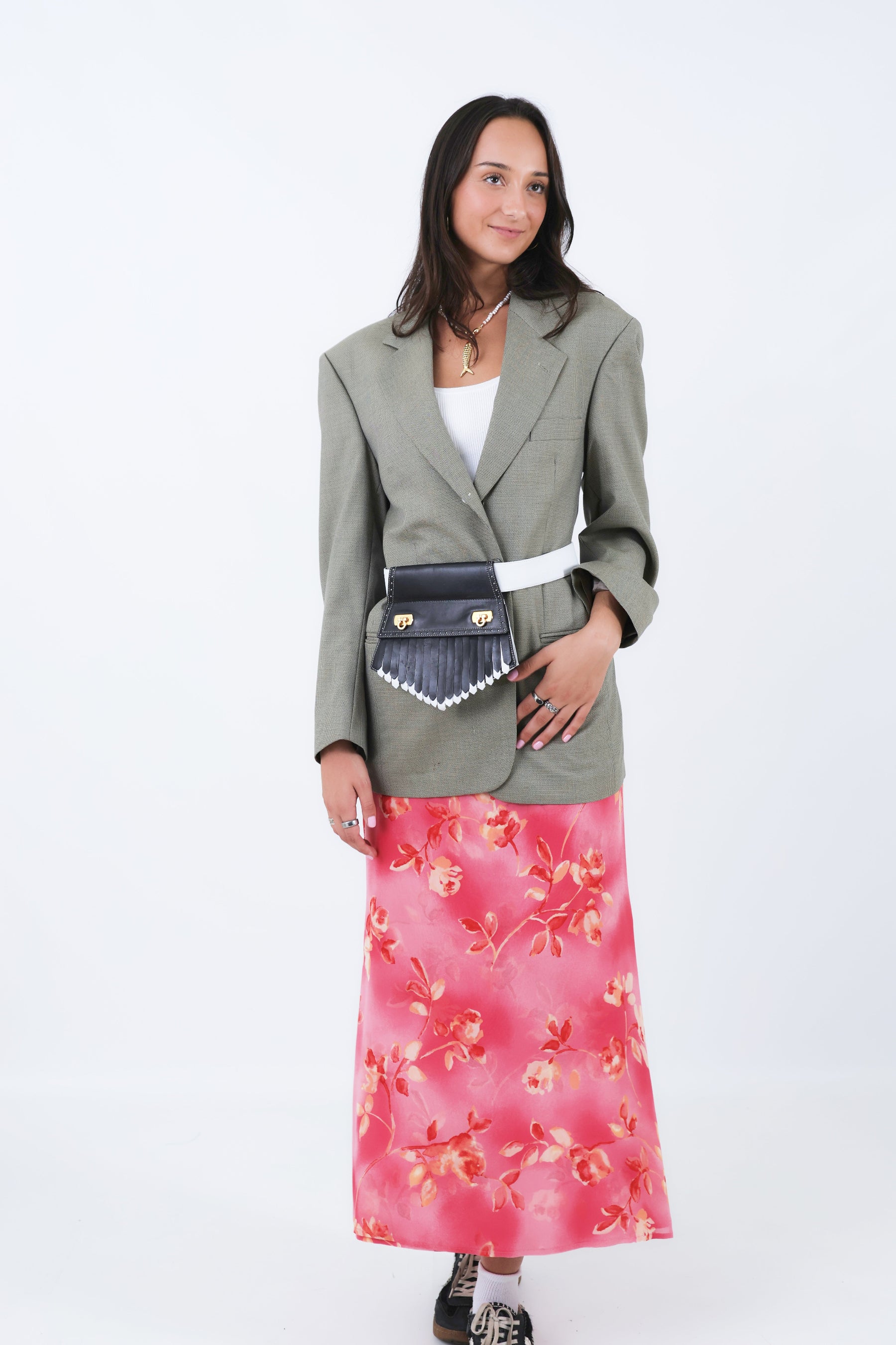 Woman wearing a gray blazer and pink floral skirt with a white background